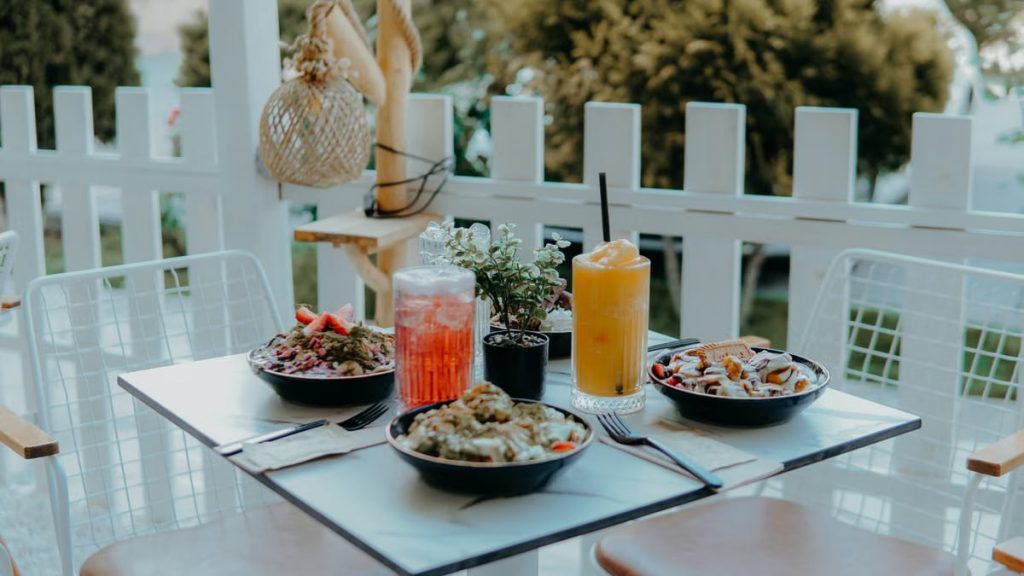 Outdoor dining setup with fresh salads and colorful drinks on a sunny day.