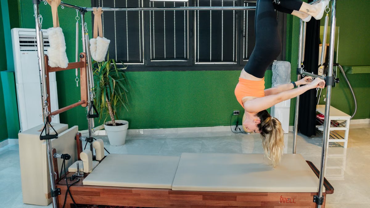 Woman practicing reformer pilates exercise in a modern fitness studio